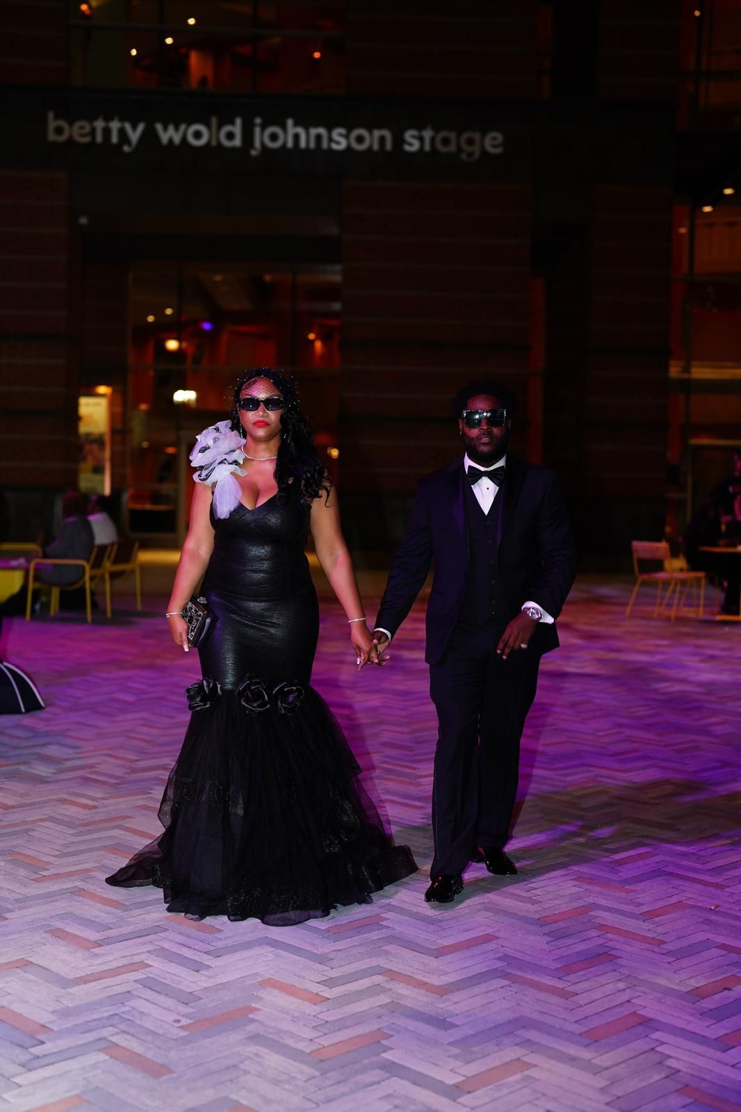 Eugene and Jessica walking hand in hand in black tie attire