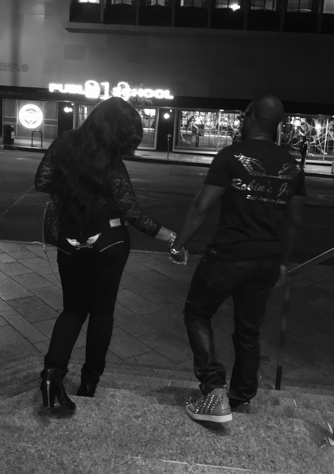 Eugene and Jessica walking hand in hand down the steps at night